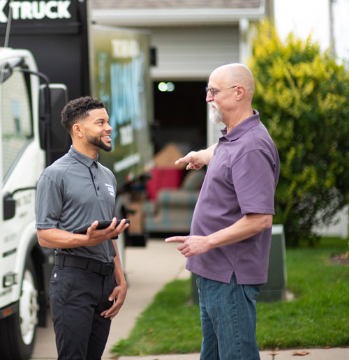 Junk removal specialist talking to senior citizen