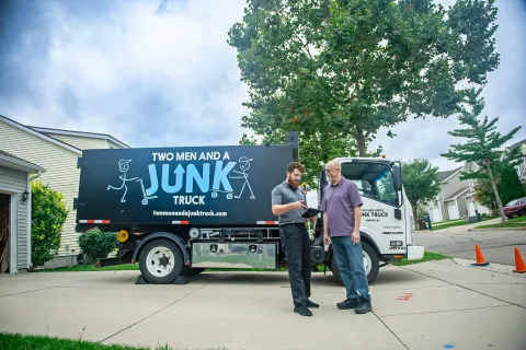 Junk Specialist talking to customer with junk container truck in the background