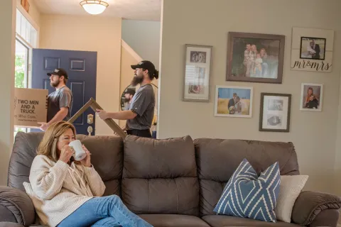Team members carrying items out while customer sits on Couch