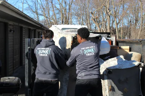 Junk Haulers loading items in the back of a junk truck in Waukesha