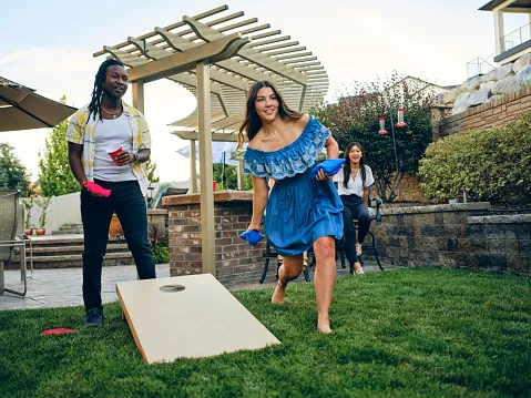 Friends playing bag toss in their organized and clean backyard area