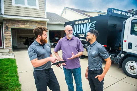 Picture of professional junk removal specialists engaging customer in front of junk truck