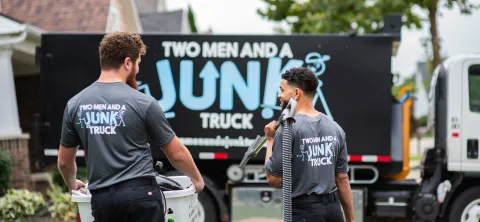 Junk removal specialists walking toward junk container truck