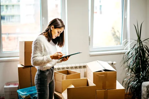 A young woman catalogs her boxes as she prepares to move out of her college apartment