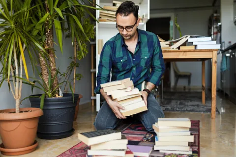 A man organizing his books and deciding what to keep and what to get rid of