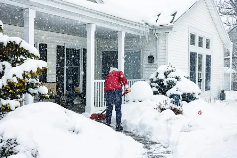 A person shoveling the driveway as part of the winter cleanup