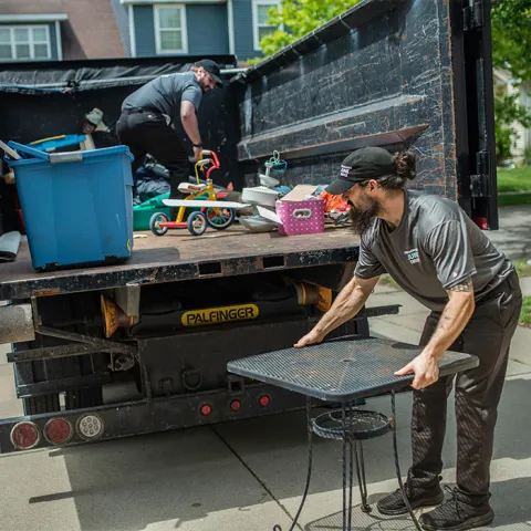 junk haulers are loading removed junk items onto the back of a junk truck