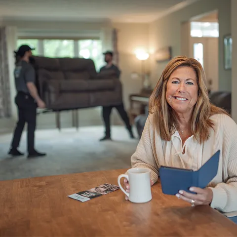junk hauler in the background performing couch removal services with the customer smiling about it