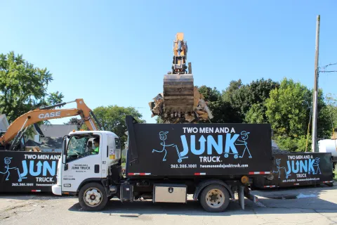 Backhoe Dumping Debris into Junk Truck