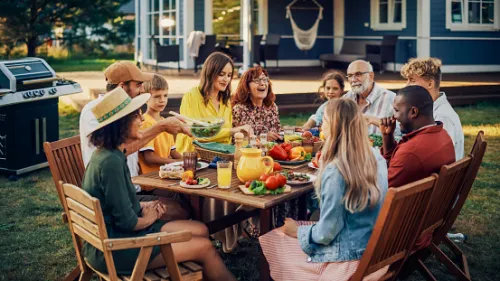 A diverse group of friends enjoying a meal together in their clean and organized lawn