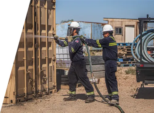 EnviroServe workers spraying down a contaminated storage container
