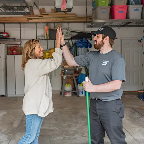 junk hauler and happy customer share high five during a garage cleanout service