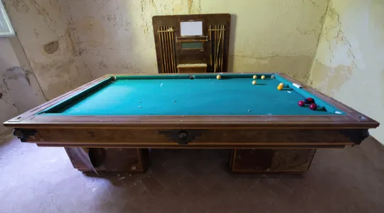 An old and slightly worn out pool table that is taking up space and needs to be removed to make space for renovation