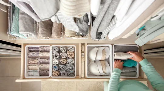 A person organizes their closet drawer.