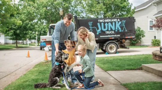 Family petting dog in front of junk truck