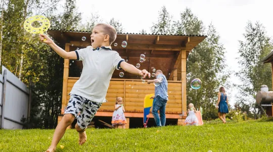 A family playing in their clean and decluttered back yard with their organized shed in the background
