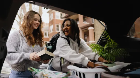 Two college students grab items from their car for move-in day