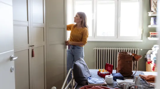Woman organizing emergency kit supplies in a bedroom